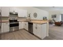 Modern kitchen with stainless steel appliances, white cabinets, wood countertops, and wood style flooring at 1065 Universal Rest Pl, Kissimmee, FL 34744