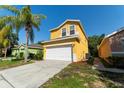 Side view of a yellow two-story home, showing the driveway, two-car garage, and landscaping details at 1129 Royal Ridge Dr, Davenport, FL 33896