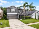 Well-maintained home with a two-car garage, green lawn, and vibrant palm trees at 13431 Early Frost Cir, Orlando, FL 32828