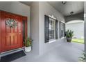 Inviting front porch featuring a red door with wreath, black shutters, and potted plants at 13431 Early Frost Cir, Orlando, FL 32828
