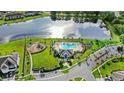 Aerial view of community amenities including a pool, playground, and clubhouse next to a lake at 15577 Willow Arbor Cir, Orlando, FL 32824