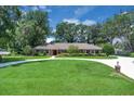 Classic brick home with a circular driveway surrounded by lush greenery and mature shade trees at 202 Riverview Dr, Longwood, FL 32779