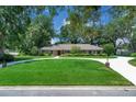 Inviting single-story home with brick exterior, manicured lawn, circular driveway, and mature landscaping at 202 Riverview Dr, Longwood, FL 32779