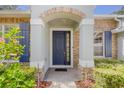 Inviting front entrance featuring a brick-arched porch and a stylish, dark blue front door at 2782 Cedar Knoll Dr, Apopka, FL 32712