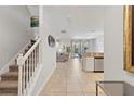 Bright hallway featuring neutral tile flooring, white walls, staircase and an open view to the kitchen and living areas at 9023 Shadow Mountain St, Davenport, FL 33896