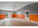 Bright living room with neutral-colored tile floors, grey and orange accent walls and a ceiling fan at 979 Mayfair St, Eustis, FL 32726