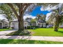 Beautifully landscaped front yard with a mature tree, green lawn, and a charming home exterior at 1173 Valley Creek Run, Winter Park, FL 32792