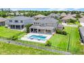 Aerial view of the backyard, with a pool, covered patio, fencing, and lush lawn at 16412 Good Hearth Blvd, Clermont, FL 34711
