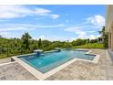 Backyard rectangular pool with tiled waterfalls, a stone patio, and green landscaping at 16412 Good Hearth Blvd, Clermont, FL 34711