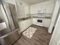 Bright kitchen featuring white cabinets, modern appliances, and wood-look flooring at 31538 Anderson Dr, Tavares, FL 32778