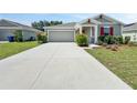 Expansive concrete driveway leading to a grey-toned home with a matching garage door and manicured front yard at 584 S Andrea Cir, Haines City, FL 33844