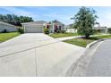 Wide driveway leads to a modern grey house with a red front door, green landscaping and a two-car garage at 584 S Andrea Cir, Haines City, FL 33844