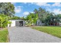 Beautiful home exterior featuring a well-maintained lawn, long driveway, and tasteful landscaping with tropical plants at 6805 Barby Ln, Belle Isle, FL 32812