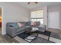 Cozy living room featuring a plush gray sectional sofa, modern rug, and bright natural light from a large window at 835 Grand Regency Pt # 104, Altamonte Springs, FL 32714
