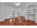 Bright living room featuring hardwood floors, French doors, and an arched window for natural light at 12713 Pine Arbor Dr, Clermont, FL 34711