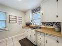 Functional kitchen featuring white cabinets, stainless steel sink, patterned backsplash, and tiled floor for a clean, classic look at 1642 Mount Vernon St, Orlando, FL 32803