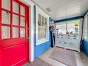 Inviting enclosed porch with bright red door, large windows, and a classic white cabinet, creating a cozy entryway at 1642 Mount Vernon St, Orlando, FL 32803