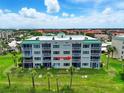 Rear exterior view of condo with screened in lanai, green lawn, and palm trees at 426 Bouchelle Dr # 202, New Smyrna Beach, FL 32169