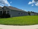 Side view of house with a pristine lawn surrounded by lush greenery at 483 Shadow Gorge Way, Eustis, FL 32736