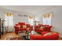 Well-decorated living room featuring plush orange seating, a glass coffee table, and decorative window treatments at 5891 Sir Henry Rd, Orlando, FL 32808