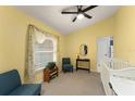 Bright bedroom with yellow walls, a large window with curtains, and comfortable seating at 7764 Indian Ridge N Trl, Kissimmee, FL 34747