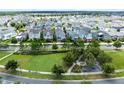 Aerial view of a residential neighborhood, showing homes, green spaces, and a lake in the background at 8290 Nemours Pkwy, Orlando, FL 32827