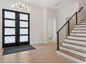 Bright entryway showcasing hardwood floors, staircase with iron railing, and stylish lighting fixture at 9156 Sheen Sound St, Orlando, FL 32836