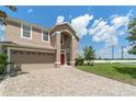 Charming two-story home with red door, beige exterior, manicured lawn and brick driveway at 10142 Serotina Ct, Orlando, FL 32832