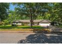 Charming single-story home with lush trees, green lawn, and a two car garage at 1111 Pinar Dr, Orlando, FL 32825