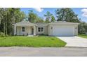 View of the home's facade, featuring a wide lawn, driveway, and attached garage at 17 Cypress Run, Haines City, FL 33844
