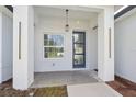 Inviting front porch featuring a modern blue door, pendant lighting, and bright natural light from the adjacent window at 17315 Sw 26Th Terrace Rd, Ocala, FL 34473