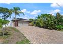 The brick driveway leads to the two-car garage of this brick accented home surrounded by tropical landscaping at 209 7Th S St, Haines City, FL 33844
