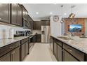 Modern kitchen with granite countertops, stainless steel appliances, dark cabinetry, and a central island at 2438 Dubai St, Kissimmee, FL 34747