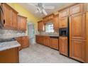 Traditional kitchen with wood cabinetry, tile backsplash, tile flooring, and sleek black appliances at 3585 Ventura Club Cir, Orlando, FL 32822