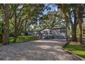 Charming single-story home featuring gray siding, a wooden deck and gravel driveway surrounded by mature trees at 411 Racoon Trl, Geneva, FL 32732