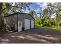 View of a two-car garage with gray metal siding and a white entry door surrounded by a grassy yard at 411 Racoon Trl, Geneva, FL 32732