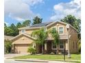 Two-story home features a well-manicured lawn, mature landscaping, and solar panels on the roof at 461 Brunswick Dr, Davenport, FL 33837
