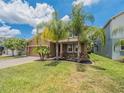 Beautiful home with lush landscaping, tropical plants, and a brick paver driveway at 461 Brunswick Dr, Davenport, FL 33837
