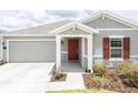 Charming home featuring a red front door, gray siding, and a covered entryway at 561 Andrea S Cir, Haines City, FL 33844