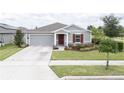 Charming single-story home with well-manicured lawn, gray siding, and a pop of color from the red front door and shutter at 561 Andrea S Cir, Haines City, FL 33844