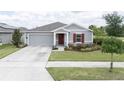 Charming single-story home with well-manicured lawn, gray siding, and a pop of color from the red front door and shutter at 561 Andrea S Cir, Haines City, FL 33844