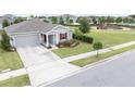Charming single-story home with well-manicured lawn, gray siding, a red front door and playground nearby at 561 Andrea S Cir, Haines City, FL 33844