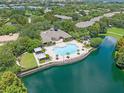 Stunning aerial view of a community pool and clubhouse overlooking a serene lake, perfect for relaxation at 6453 Alcalde Ct # 110, Orlando, FL 32835