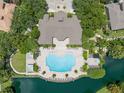 Aerial view of a luxurious community pool surrounded by lush landscaping and waterfront views at 6453 Alcalde Ct # 110, Orlando, FL 32835