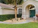 Inviting home entrance with a manicured lawn, stone landscape features, and a vibrant green front door at 14322 Pine Cone Trl, Clermont, FL 34711