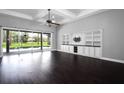 Spacious living room with dark wood floors, a ceiling fan, and a wall of built-in cabinets at 1441 Foxtail Ct, Lake Mary, FL 32746