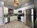 Well-lit kitchen featuring stainless appliances, white cabinets, mosaic backsplash, and tiled floor at 1470 Daniels Cove Dr, Winter Garden, FL 34787