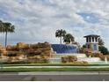 Beautiful Waterleigh community entrance with a water feature, palm trees, and a decorative structure at 15500 Fountain Cove Ct, Winter Garden, FL 34787