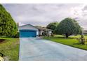 Single-story home with blue trim, blue driveway and mature trees enhance the curb appeal of this well-maintained property at 2334 W Doris St, Kissimmee, FL 34741