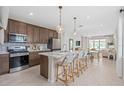 Modern kitchen features an island with bar seating, stainless steel appliances, and a view into the dining and living areas at 2338 Lily Bloom Rd, St Cloud, FL 34771